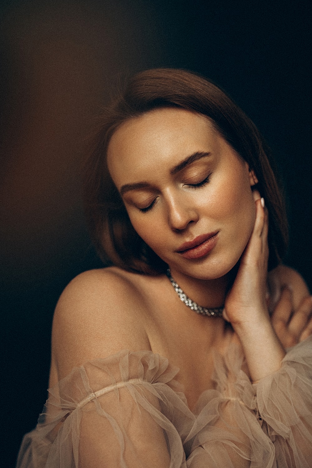 Woman with closed eyes, soft expression, elegant attire.