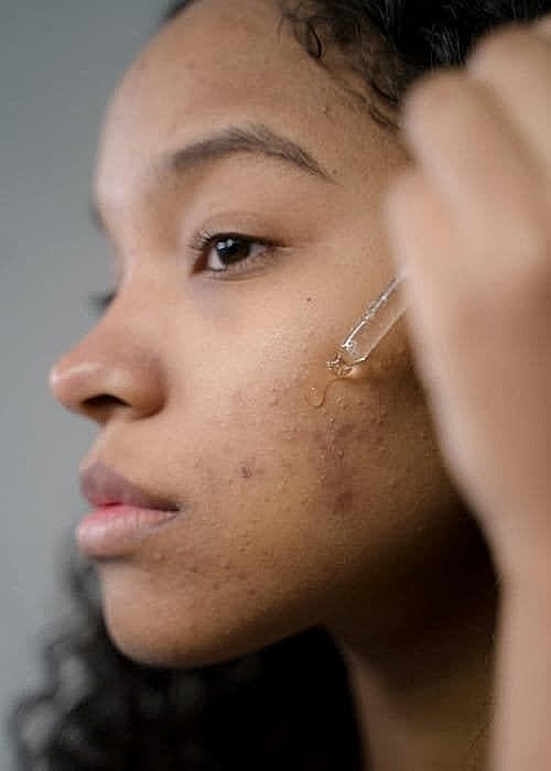 Applying serum to skincare routine on face.